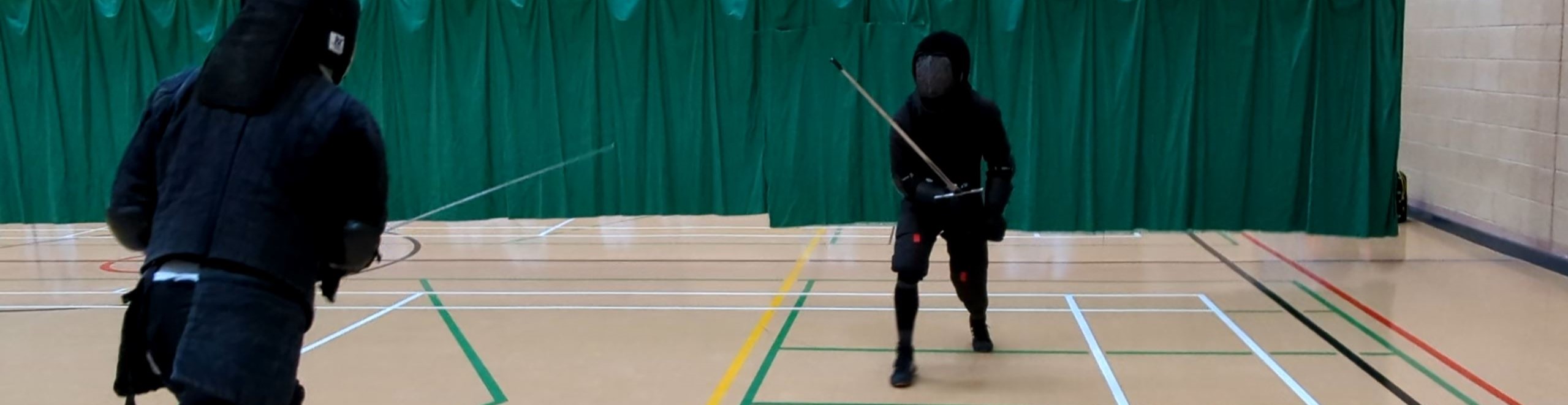 Two fencers in full gear, approaching each with longswords ready